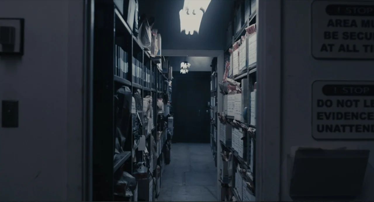 Beyond a Reasonable Doubt (2009) movie still: wide — A narrow evidence room corridor features metal shelving packed with documented case files. The…