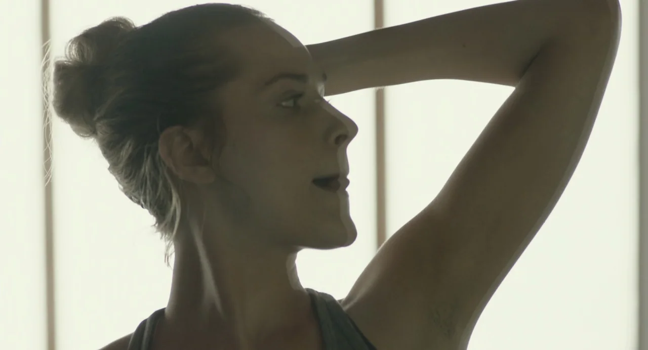 En lo profundo del bosque movie still: closeup — A brightly lit interior space features a woman standing against a diffuse white background. She…