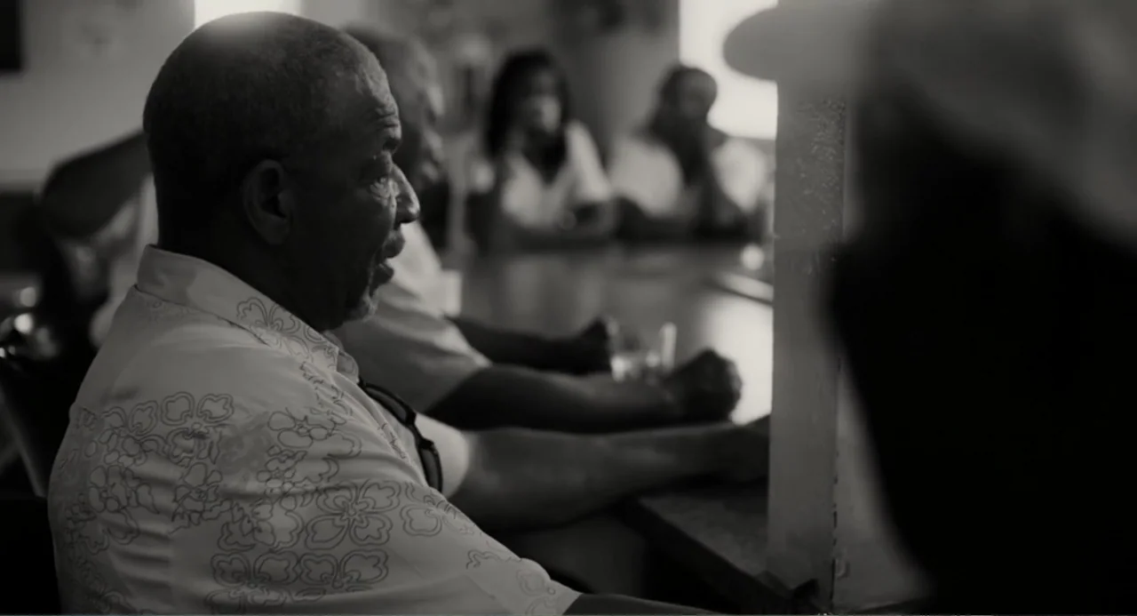 What You Gonna Do When the World's on Fire? (2019) movie still: medium — A group of people sit around a table in a brightly lit indoor space. A man…
