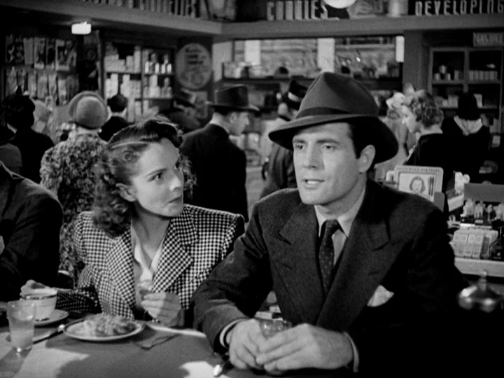 Stranger on the Third Floor (1940) movie still: medium — A 1940s diner interior features shelves with product labels and crowded booths behind them.…