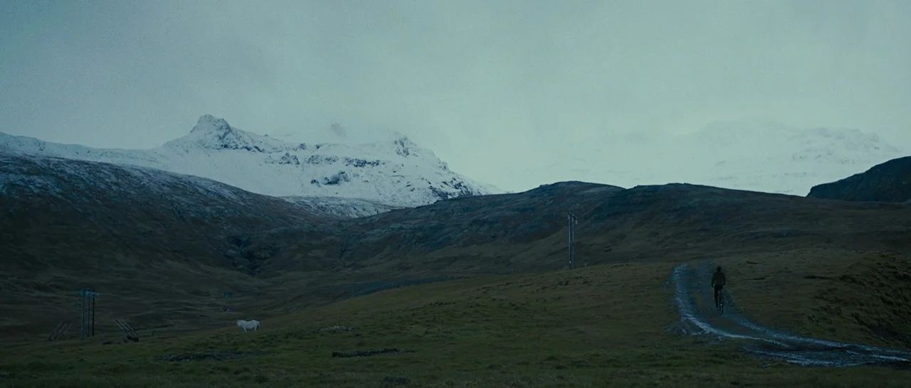 Pawn Sacrifice (2014) movie still: wide — A vast, desolate landscape features snow-capped mountains under a heavy overcast sky. A lone person on a…