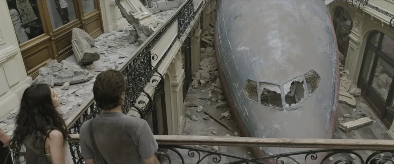 Darkest Hour (2017) movie still: medium — A damaged multi-level shopping arcade contains a large crashed airplane fuselage resting on the ground.…
