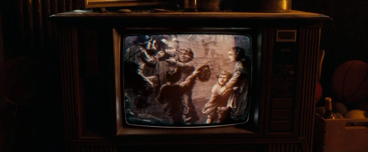 Trick ‘R Treat (2007) movie still: closeup — A wooden console television sits in a darkened room with a static image displayed. The screen depicts a…
