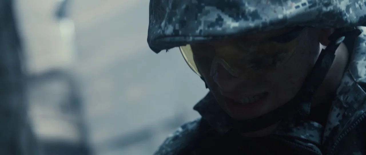 Universal Soldier: Regeneration (2009) movie still: closeup — A soldier in digital camouflage combat gear gazes downward in a grey outdoor…