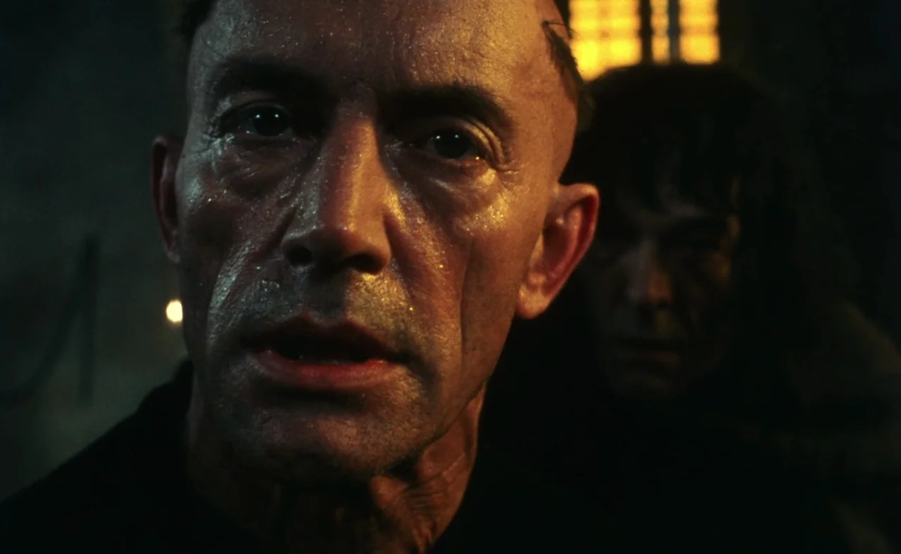 The Pit and The Pendulum (1991) movie still: closeup — A close-up shot of a man's face in a dark, stone-walled space. The man looks directly ahead…