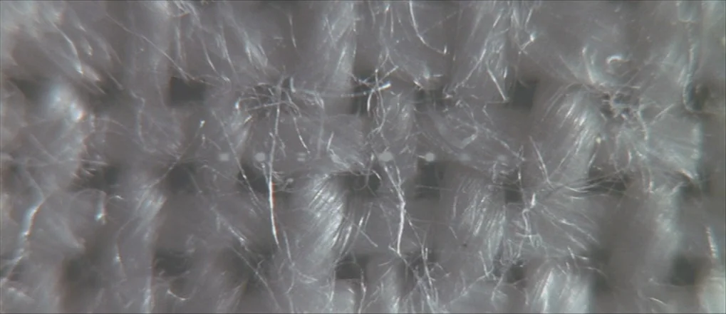 Insomnia (2002) movie still: closeup — A extreme close-up view shows the textured weave of a synthetic fabric. Thin individual translucent fibers…
