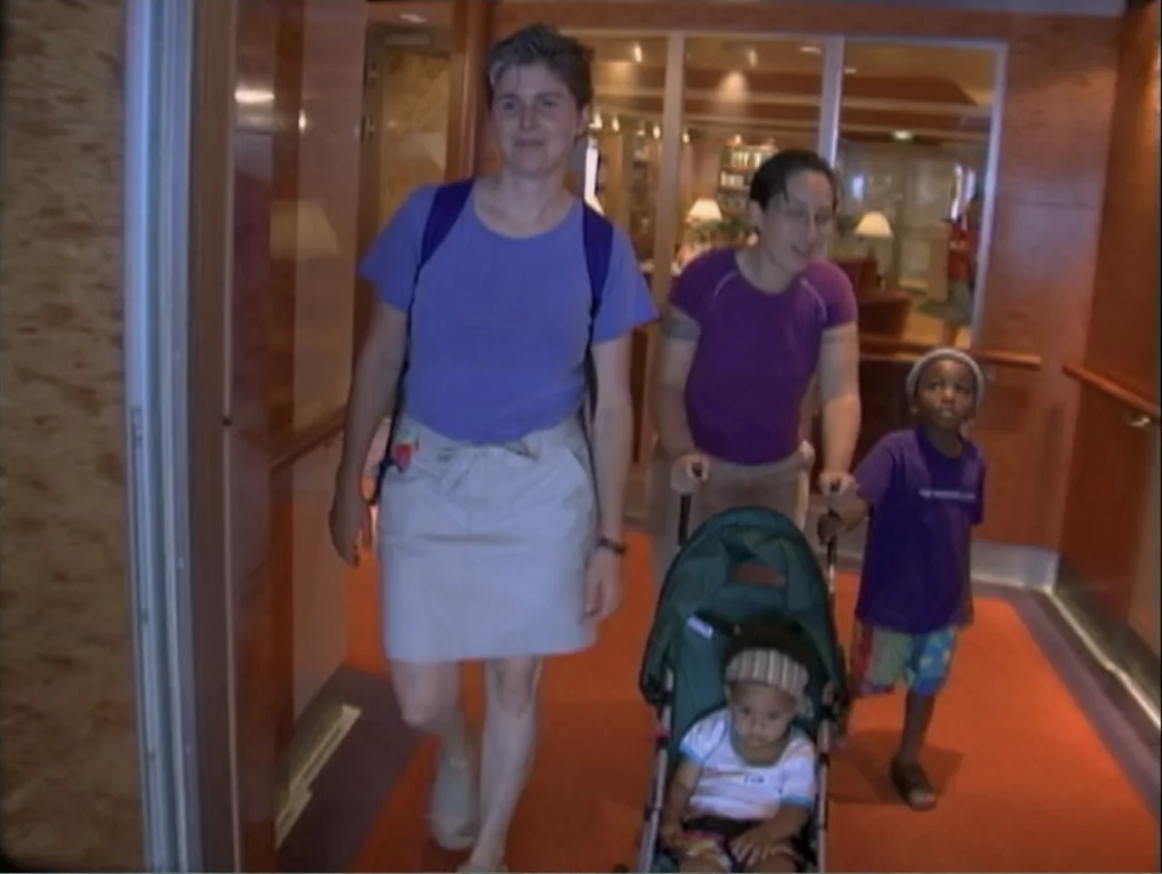 All Aboard! Rosie's Family Cruise (2006) movie still: fullbody — A well-lit interior corridor features an orange carpet and paneled walls with glass…