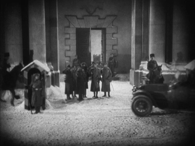 The Last Command (1928) movie still: wide — A snowy courtyard featuring a large stone building entrance with a central doorway. Soldiers in winter…