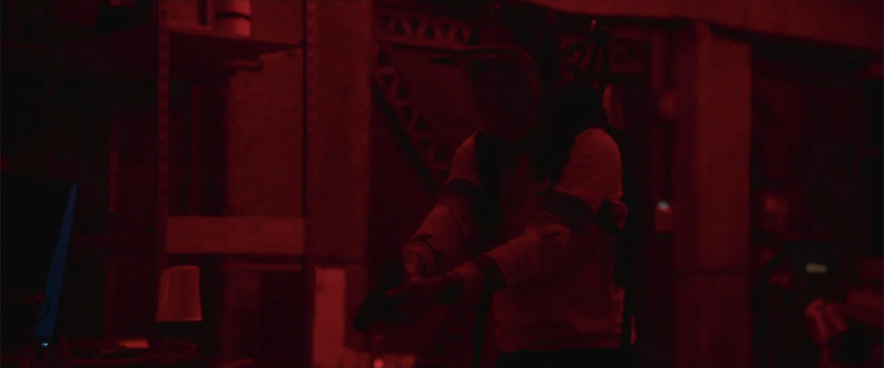Breathe (2011) movie still: medium — An industrial storage room featuring metal shelving units and dark architectural support beams. A woman wearing…