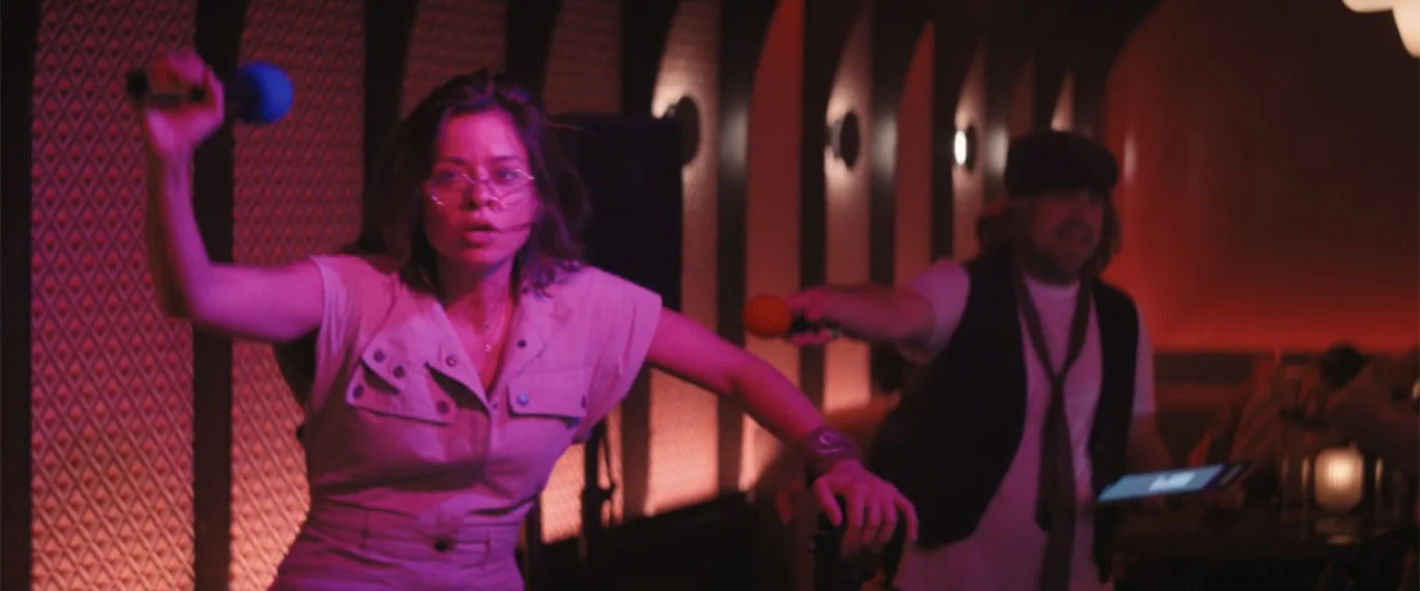 The Fall Guy (2024) movie still: medium — A dimly lit room features dark arched architectural details and a geometric patterned wall. A woman and…