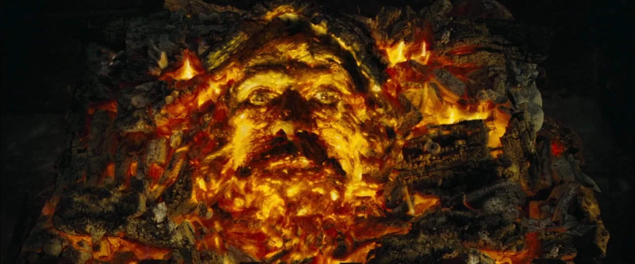Harry Potter and the Goblet of Fire (2005) movie still: closeup — A pile of burning charcoal and wood forms the shape of a human face. The face is…