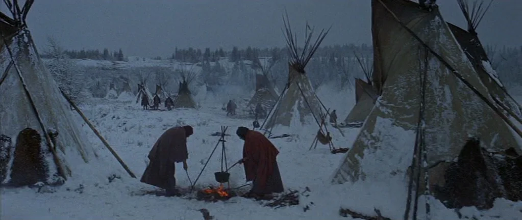 Little Big Man (1970) movie still: wide — A snow-covered encampment features multiple conical structures arranged across a cold, barren landscape.…