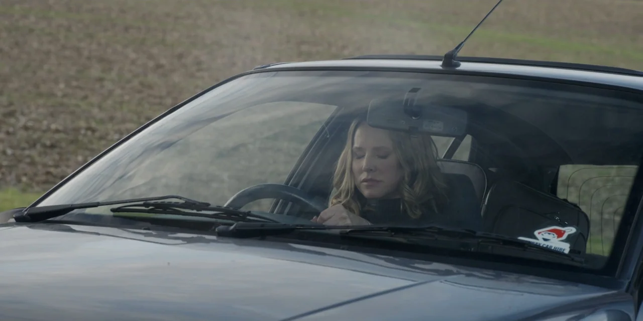 The People We Hate at the Wedding (2022) movie still: medium — A woman sits in the driver seat of a car parked in a field. The woman sits with her…