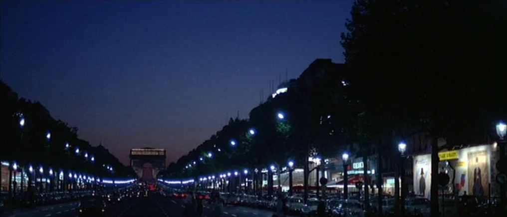 Pierrot Le Fou (Crazy Pete) (1965) movie still: establishing — A wide avenue at night with rows of illuminated streetlamps leading toward a distant…