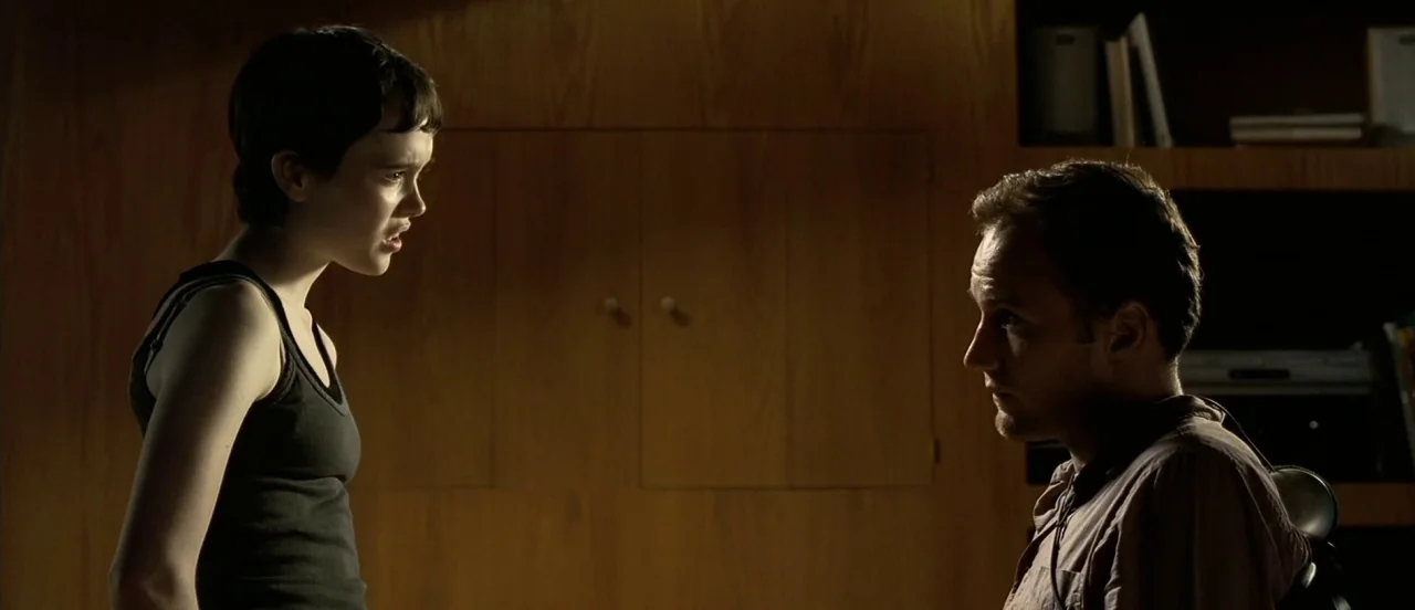 Hard Candy (2005) movie still: medium — An interior space features wood-paneled walls and built-in shelving units in the background. A young woman…