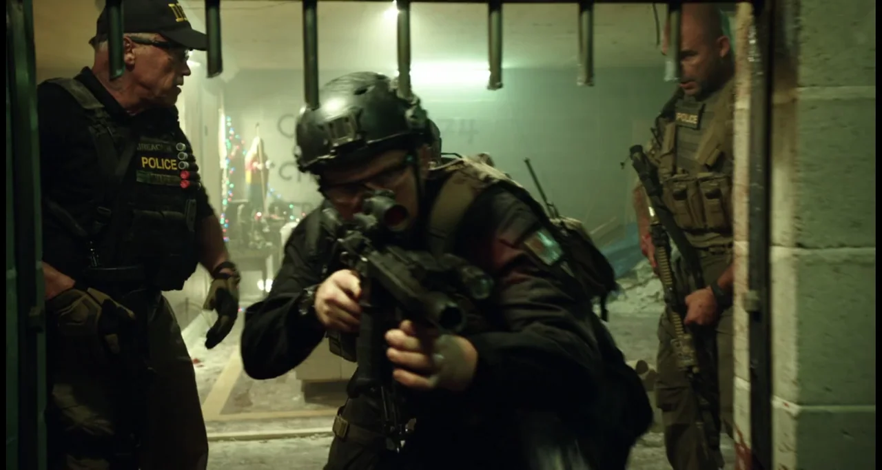 Sabotage (2014) movie still: medium — A dimly lit industrial room contains tactical officers entering through a barred door. The three armed men…