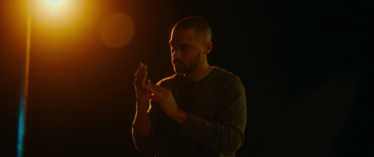 Random Acts of Violence (2019) movie still: medium — A dark outdoor setting illuminated by the glow of a streetlamp at night. A man examines his…