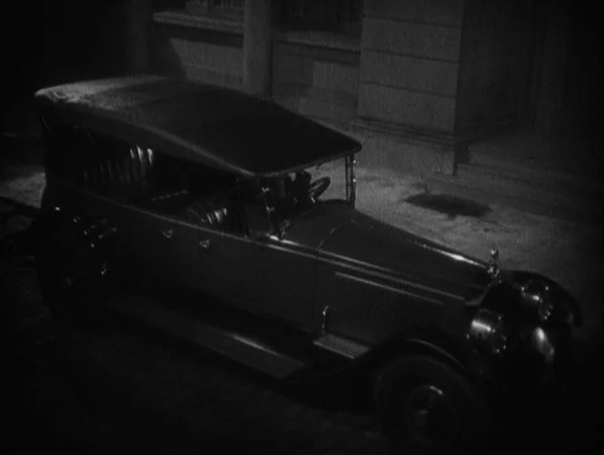 Underworld (1927) movie still: wide — A vintage 1920s touring car is parked on a dark cobblestone path at night. The vehicle sits empty against a…