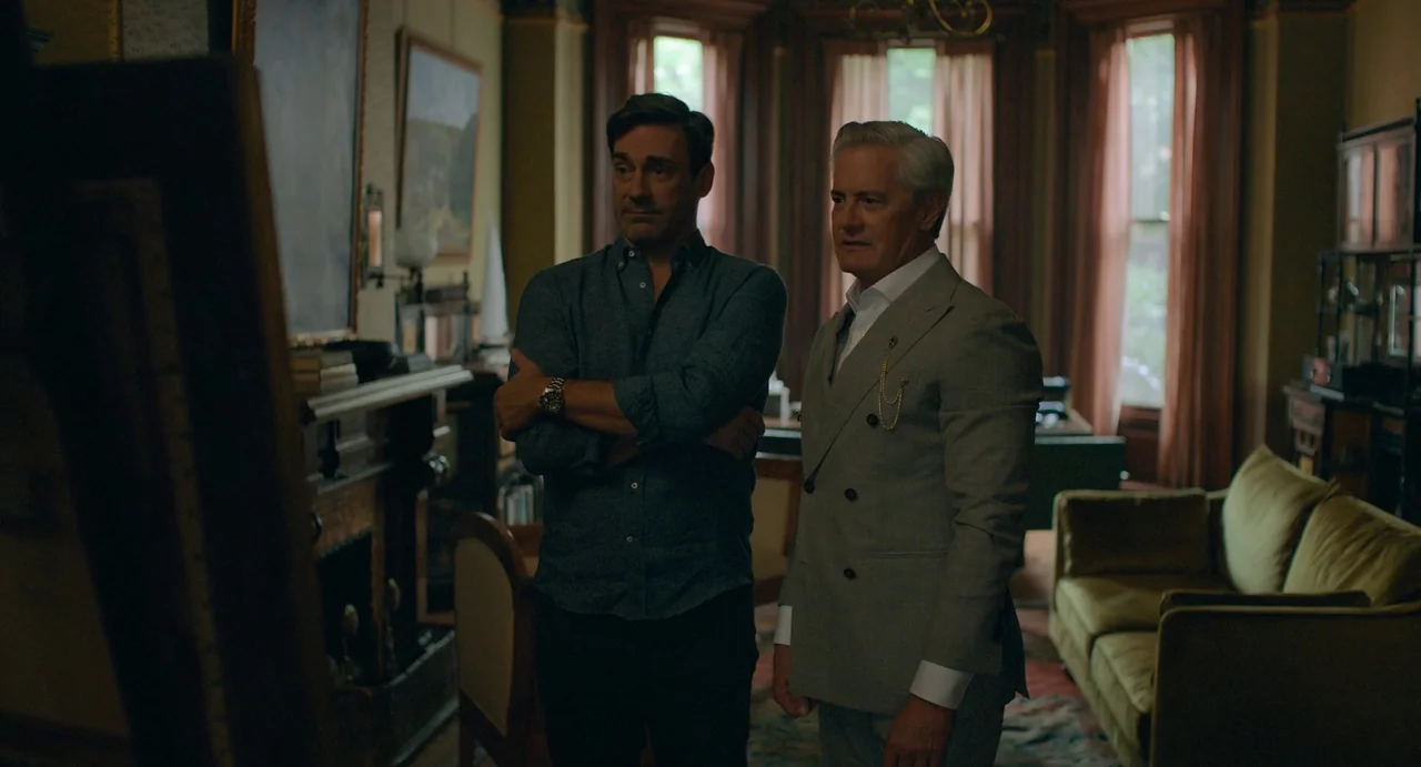 Confess, Fletch (2022) movie still: medium — A dimly lit Victorian-style parlor features wooden furniture and heavy drapes covering tall windows.…