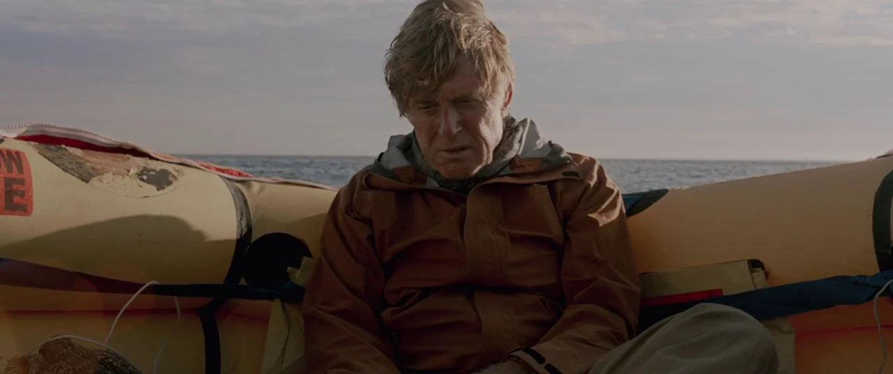 All Is Lost (2013) movie still: medium — An aging man sits inside a yellow inflatable life raft on the open sea. He is positioned in the center,…