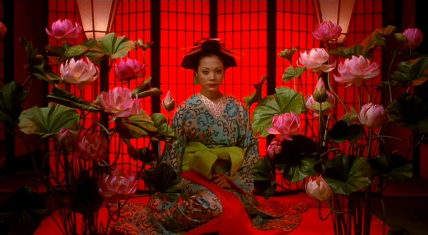 Sakuran (2006) movie still: medium — A room features a grid-patterned red backdrop with two large paper lamps. A woman in a patterned kimono sits…