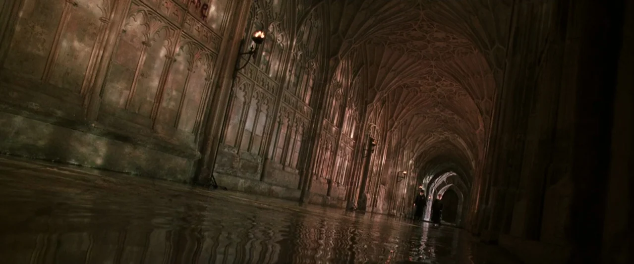 Harry Potter and the Chamber of Secrets (2002) movie still: wide — A long, vaulted stone corridor features ornate Gothic architecture and dark,…
