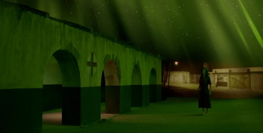 Dominion: Prequel to the Exorcist (2005) movie still: wide — A worn building with multiple archways features a painted medical cross symbol on its…