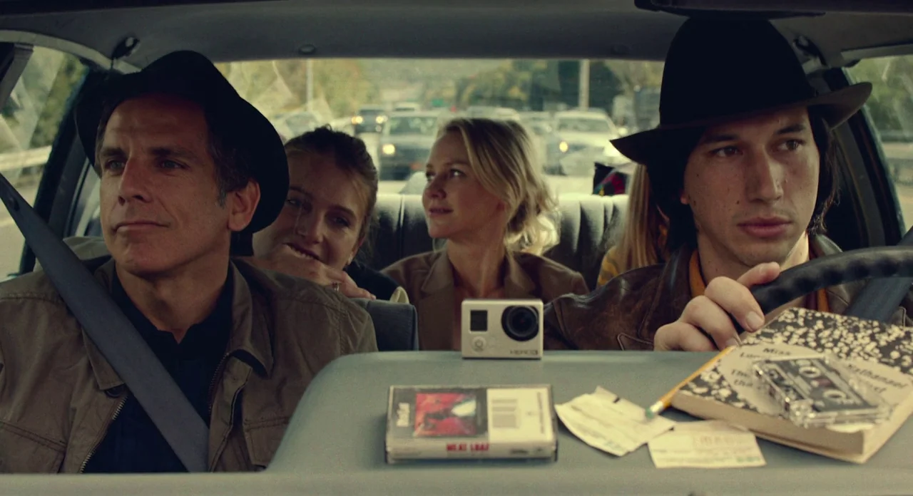 While We’re Young (2014) movie still: medium — The interior of a car during a daytime drive on a highway. Two men in fedoras occupy the front seats,…
