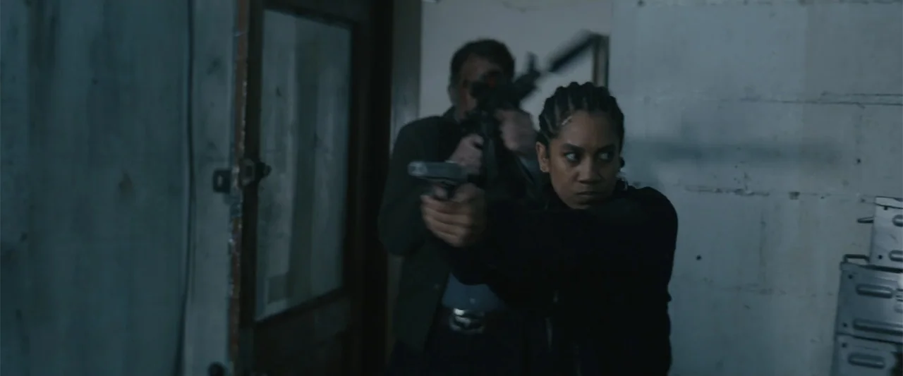 One Ranger (2023) movie still: medium — An interior industrial corridor features white cinderblock walls and a dark wooden door frame. A woman and a…