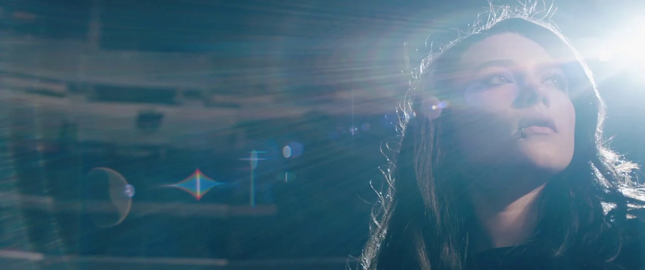 Fighting With My Family (2019) movie still: closeup — A dark outdoor space features blurred tiered seating structures in the out-of-focus…