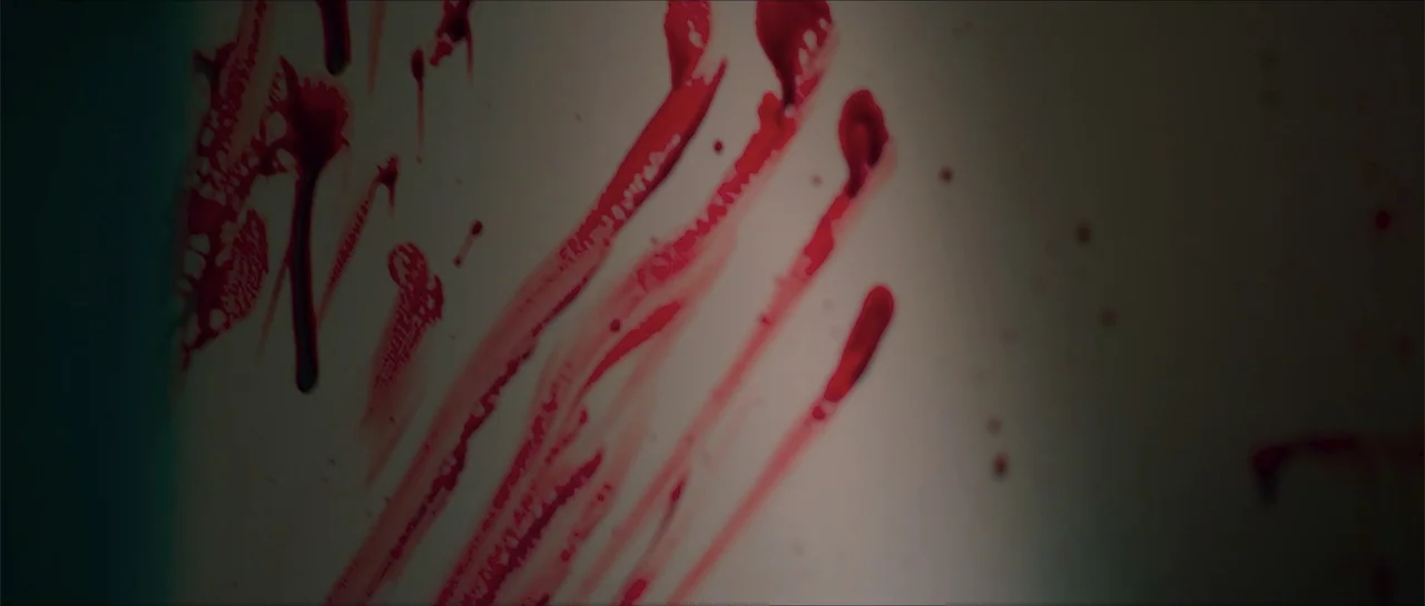 68 Kill (2017) movie still: closeup — A close-up view of a smooth, light-colored wall surface with vertical markings. Bright red liquid streaks flow…