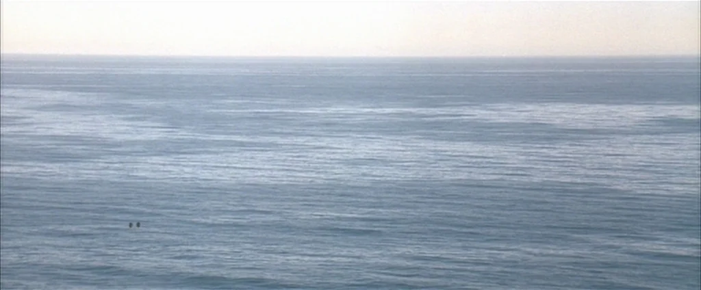 Down In The Valley (2005) movie still: establishing — A vast, calm expanse of blue ocean stretches out to a distant, hazy horizon. The water surface…