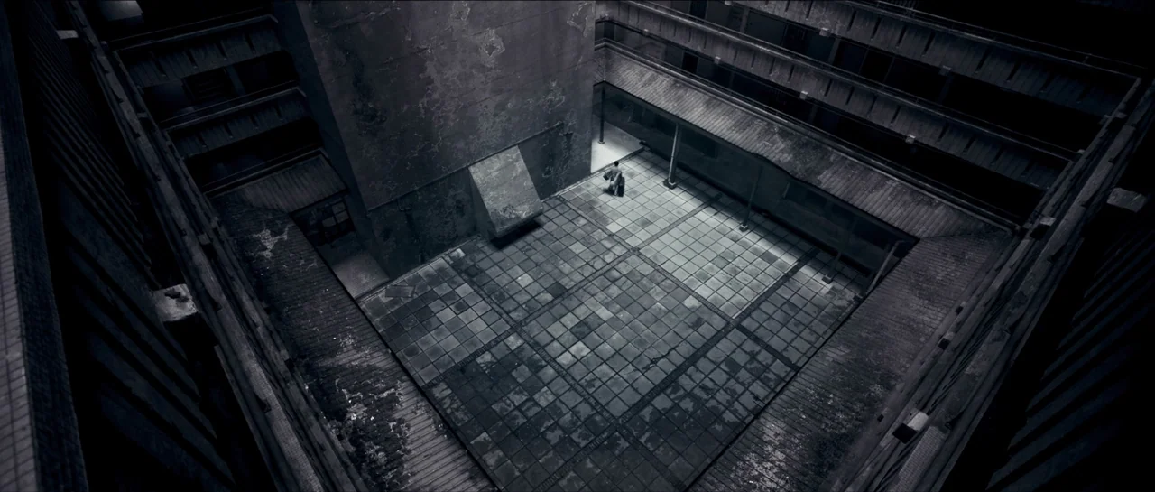 Rigor Mortis (2013) movie still: establishing — A dark, multi-level apartment complex features a central tiled courtyard with weathered concrete…