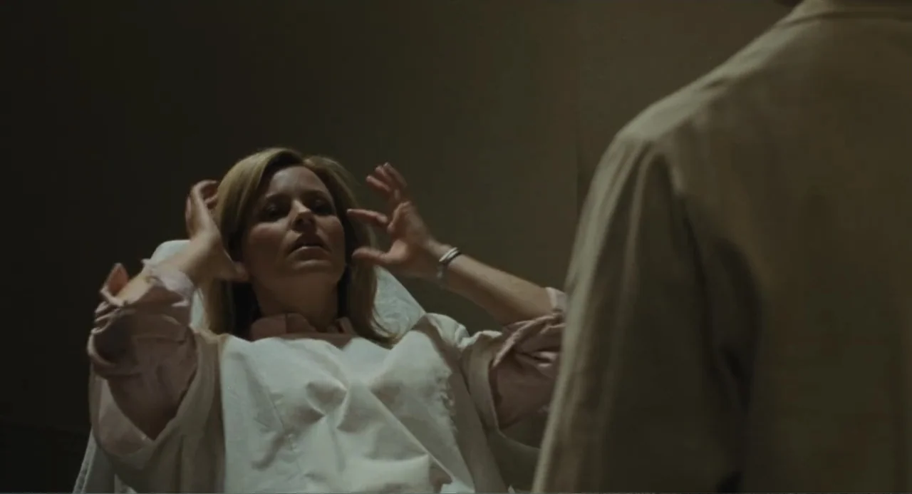 Call Jane (2022) movie still: medium — A sterile medical examination room features plain walls and a treatment table. A woman in a hospital gown…