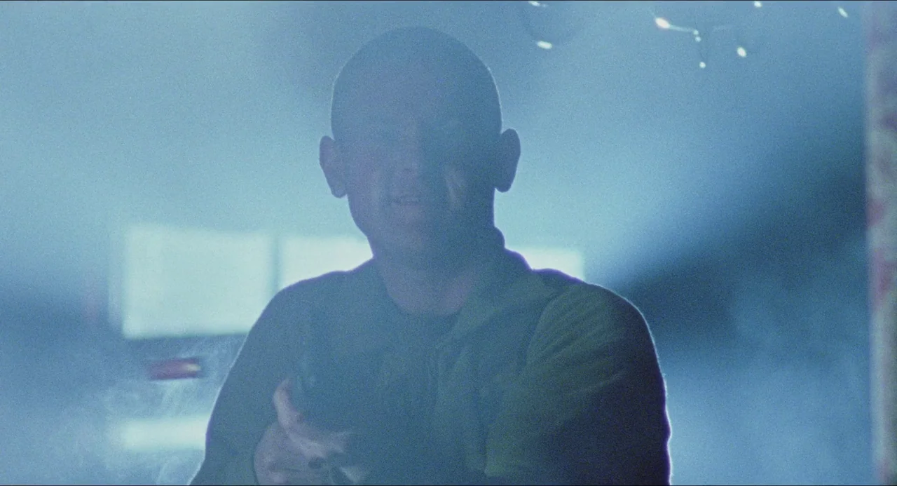 Dog Soldiers (2002) movie still: medium — A dimly lit room is filled with thick atmospheric haze and blue light. A man holds a pistol directly…