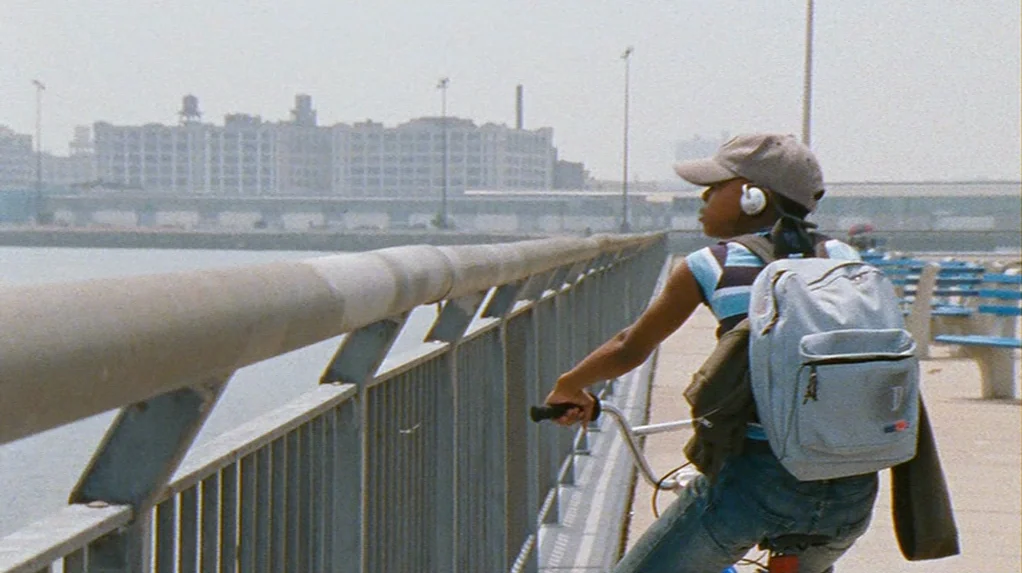 Half Nelson (2006) movie still: medium — A concrete pier stretches toward an industrial cityscape under a hazy, bright daytime sky. A teenage boy on…