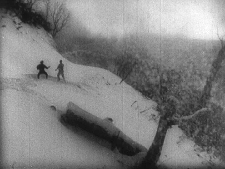 Sanshiro Sugata Part II (1945) movie still: wide — A snow-covered, steep mountain slope features a large fallen log in the foreground. Two figures…