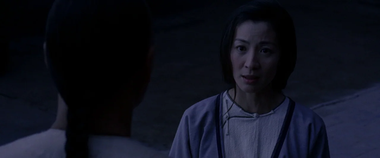 Crouching Tiger, Hidden Dragon (2000) movie still: medium — A dimly lit exterior courtyard at night with cool blue ambient tones. One woman stands…