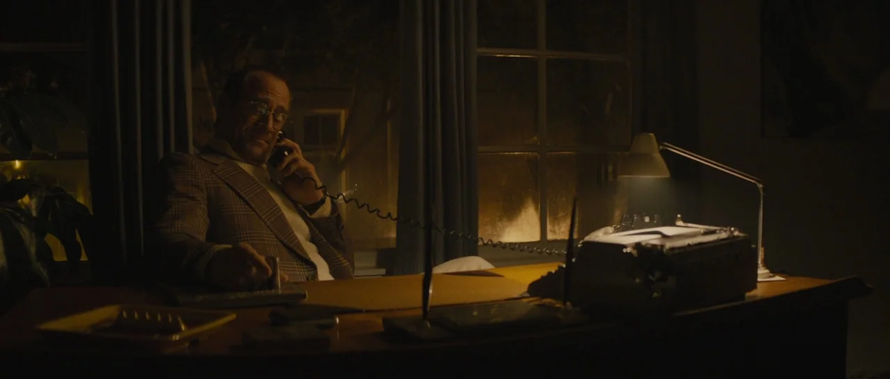 The Diary of a Teenage Girl (2015) movie still: medium — A dimly lit office at night features a large wooden desk holding a typewriter. A man sits…