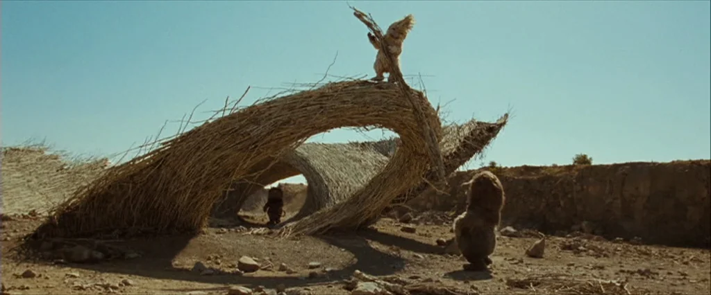 Where The Wild Things Are (2009) movie still: wide — An arid desert expanse features an elaborate, arched structure built from bundled dry straw.…