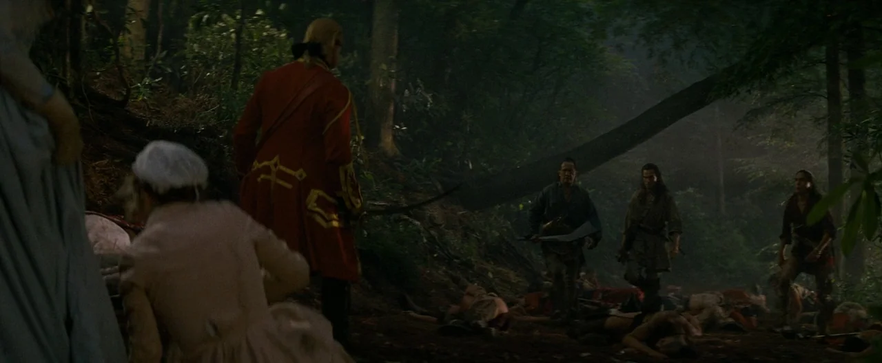 The Last of the Mohicans (1992) movie still: wide — A dense woodland clearing contains scattered bodies strewn across the dark dirt ground. A…
