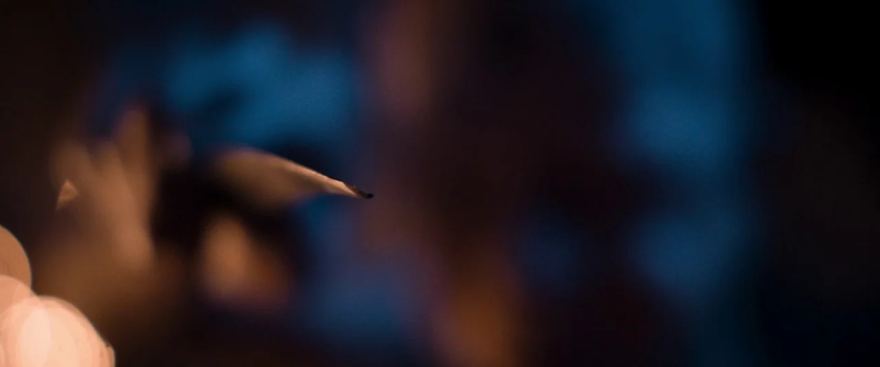 Baskin (2015) movie still: closeup — A dark, out-of-focus scene with blue hues features a single sharp, bright point. The sharp tip of a metallic…