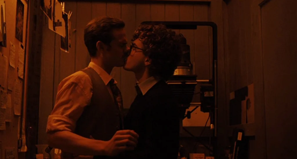 Milk (2008) movie still: medium — A cramped darkroom filled with photographic equipment and papers pinned to wooden walls. Two young men stand close…