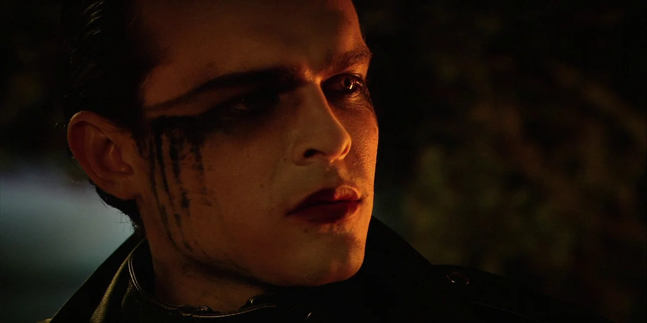 Twixt (2011) movie still: closeup — An outdoor nighttime scene featuring a man with dark, smeared makeup on his face. He is illuminated by a warm,…