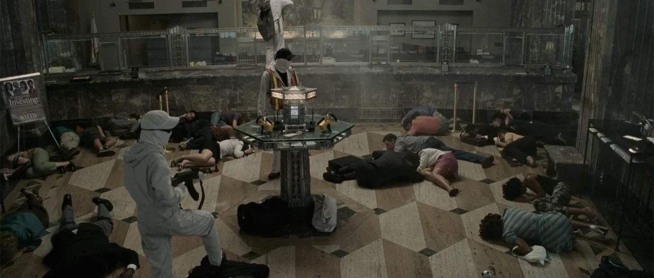 Inside Man (2006) movie still: wide — A spacious bank lobby features marble floors and high-teller windows in the background. Multiple hostages lie…