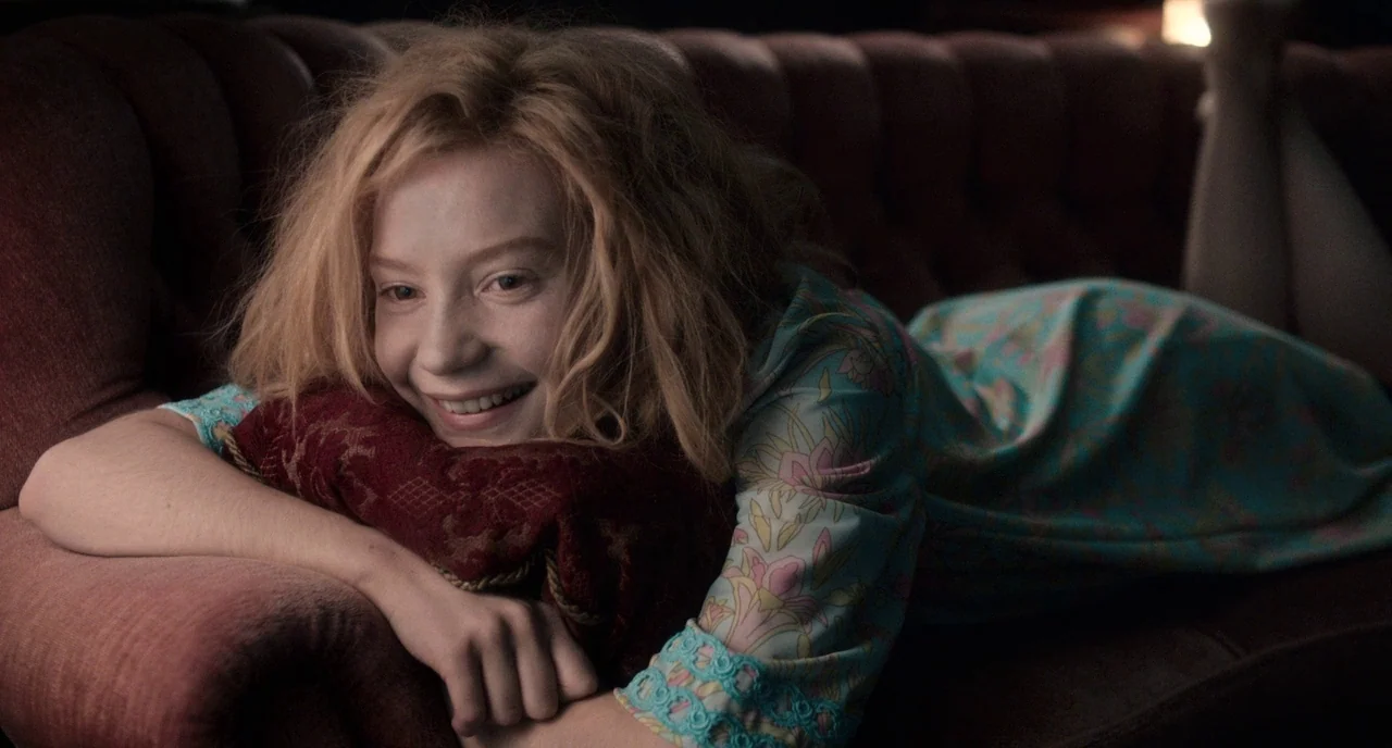 Only Lovers Left Alive (2013) movie still: medium — A woman lies on a large, dark-colored tufted sofa in a dimly lit room. She rests her chin on a…