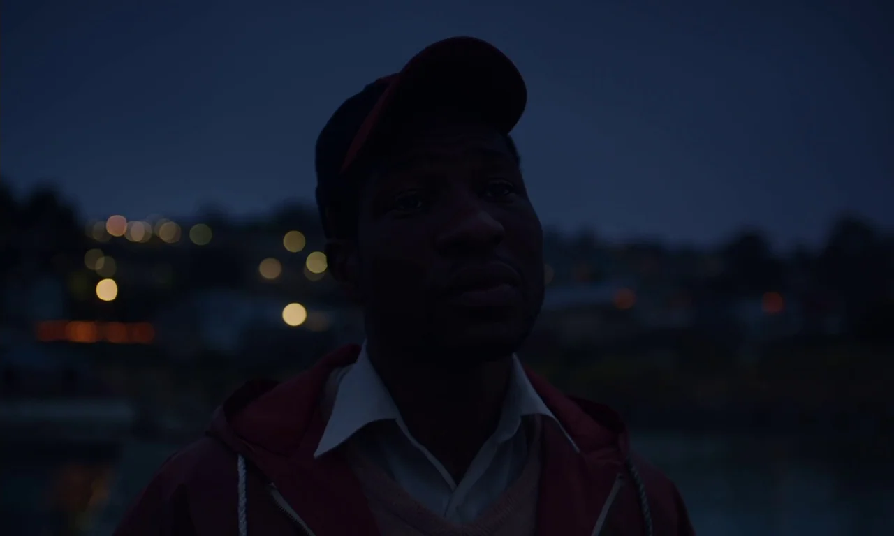 The Last Black Man in San Francisco (2019) movie still: closeup — A dark outdoor setting features a man standing before a distant, blurred city…