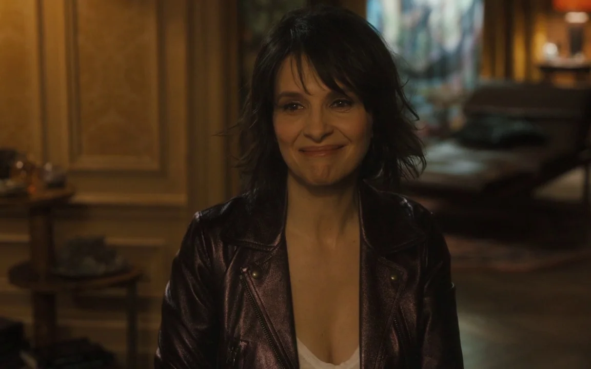 Let The Sunshine In (2017) movie still: medium — A dimly lit room features traditional paneled walls and warm ambient light sources. A woman with…