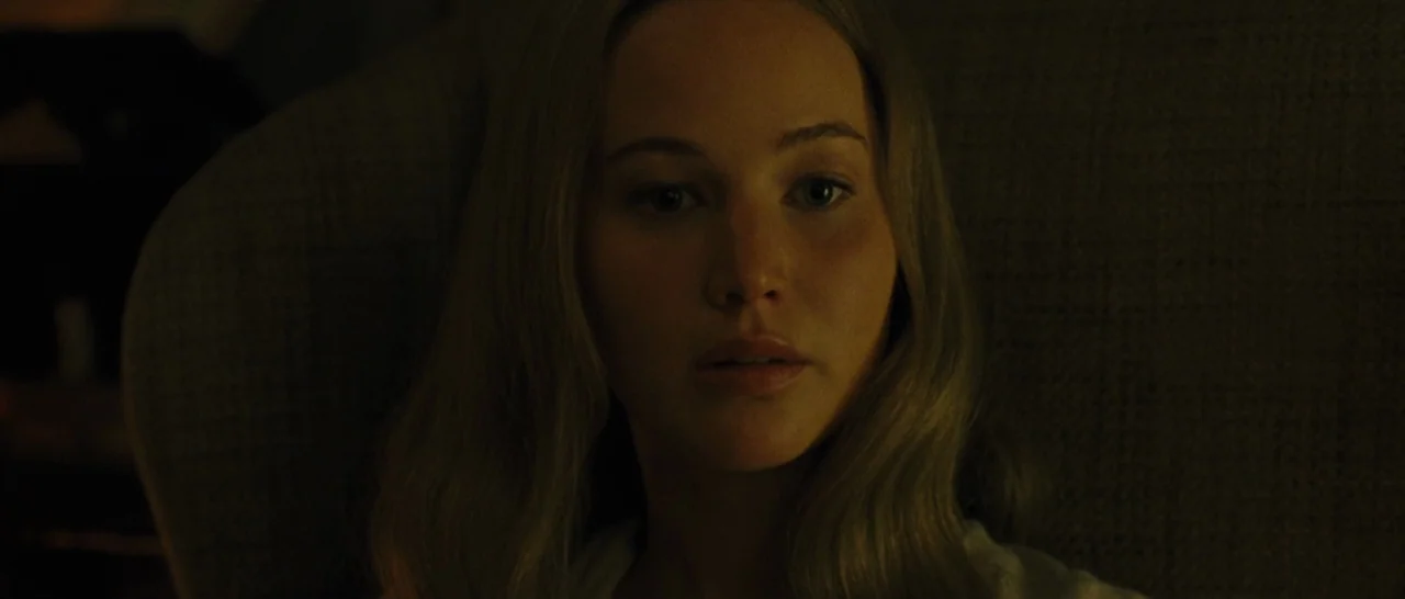 mother! (2017) movie still: closeup — A dark indoor space with minimal ambient light defining the foreground. A woman rests her head against a…