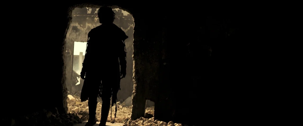 Resident Evil: The Final Chapter (2016) movie still: fullbody — A dark, rubble-filled interior space looks out toward a bright, sunlit outdoor area.…